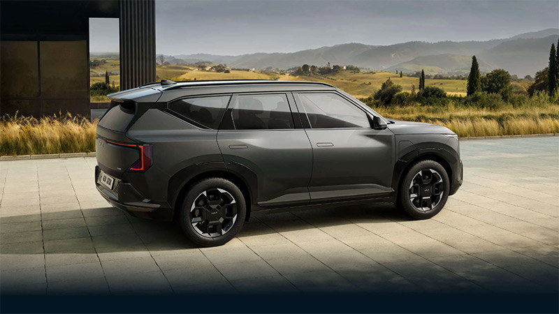 Šedý model vozu Kia EV5 zaparkovaný před budovou v přírodě