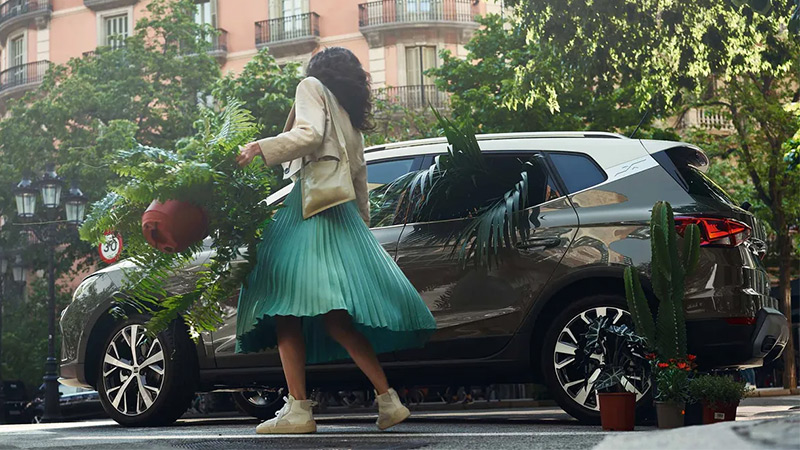Žena s kytkou v květináči nastupuje do vozu SEAT Arona