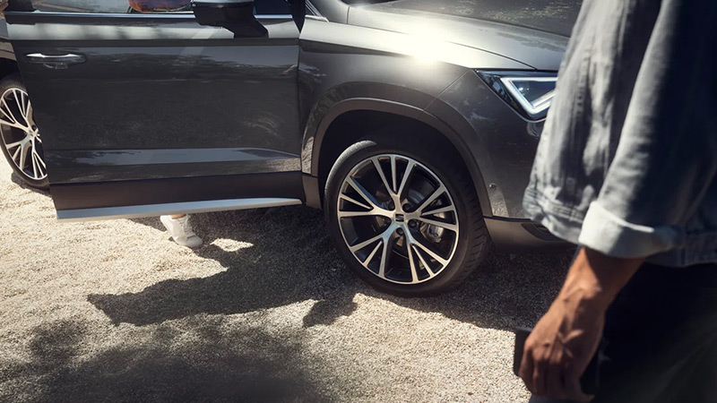 Šedý model SEAT Ateca, detail kola, kolem prochází muž