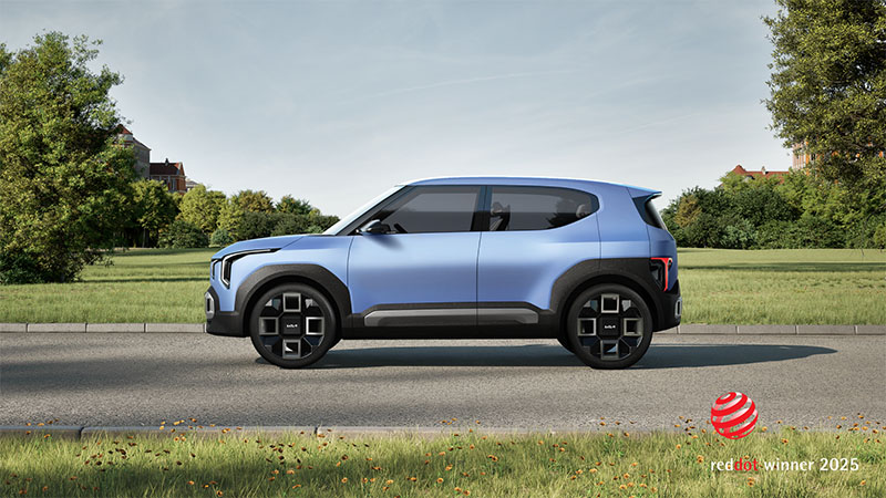 Modrý koncept elektromobilu Kia EV2, focený z boku na silnici v zelené krajině