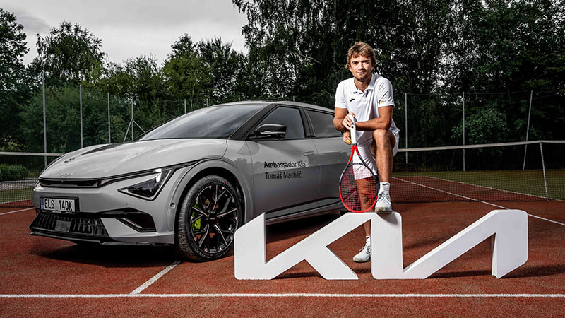 Tomáš Macháč s tenisovou raketou u auta Kia EV6 GT na tenisovém kurtu