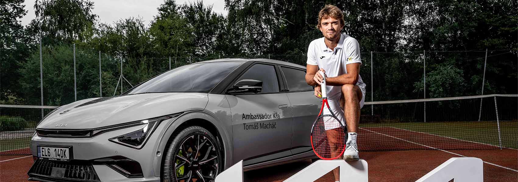 Tomáš Macháč s tenisovou raketou u auta Kia EV6 GT na tenisovém kurtu