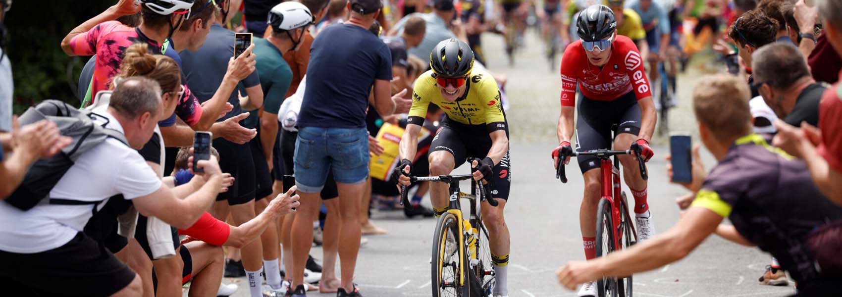 Cyklisté v závodě Czech Tour 2025 projíždějí mezi fanoušky, kteří stojí podél trati